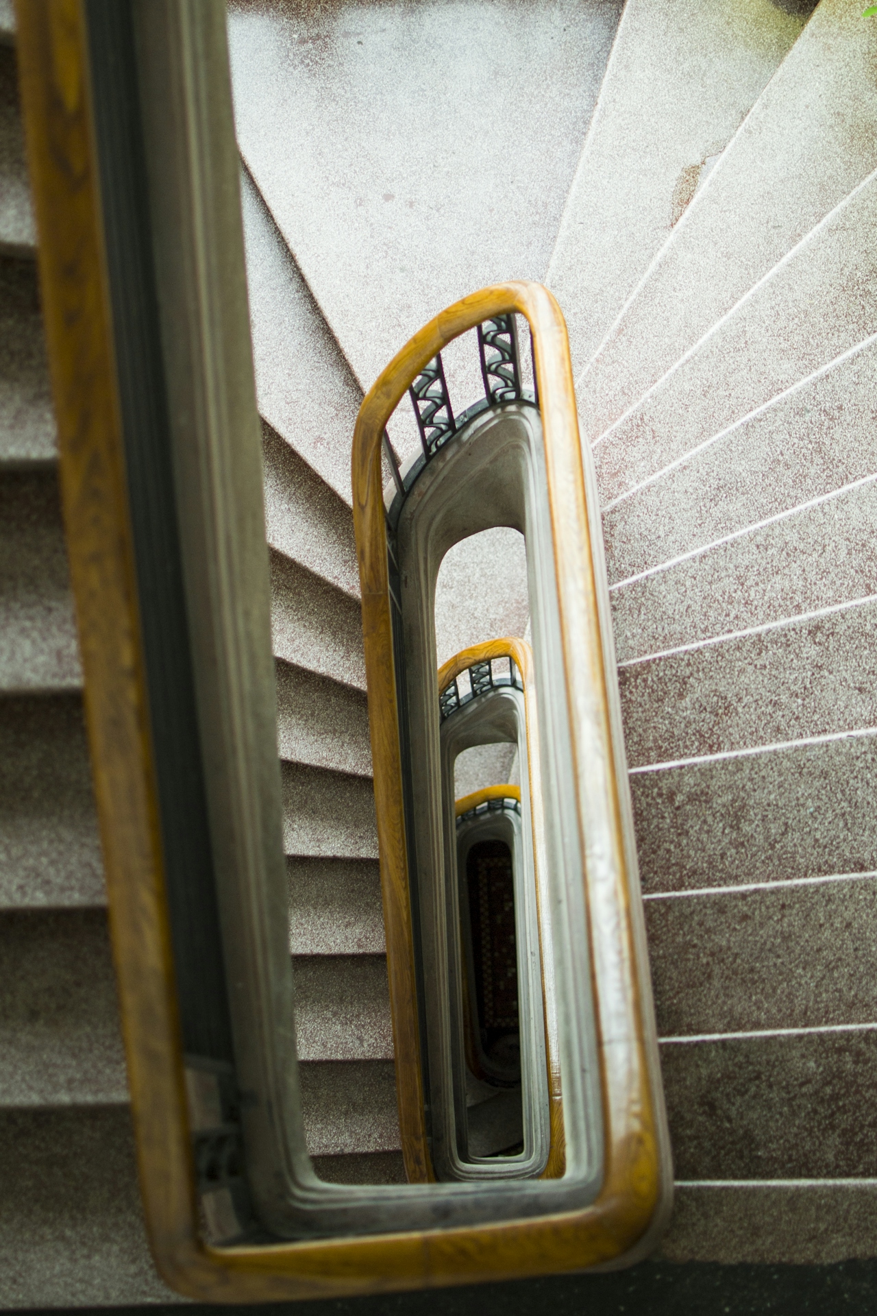 Treppen- und Aufgangsreinigung Schöne, spiralförmige Treppe mit orangefarbenen Geländern und grauen Stufen.