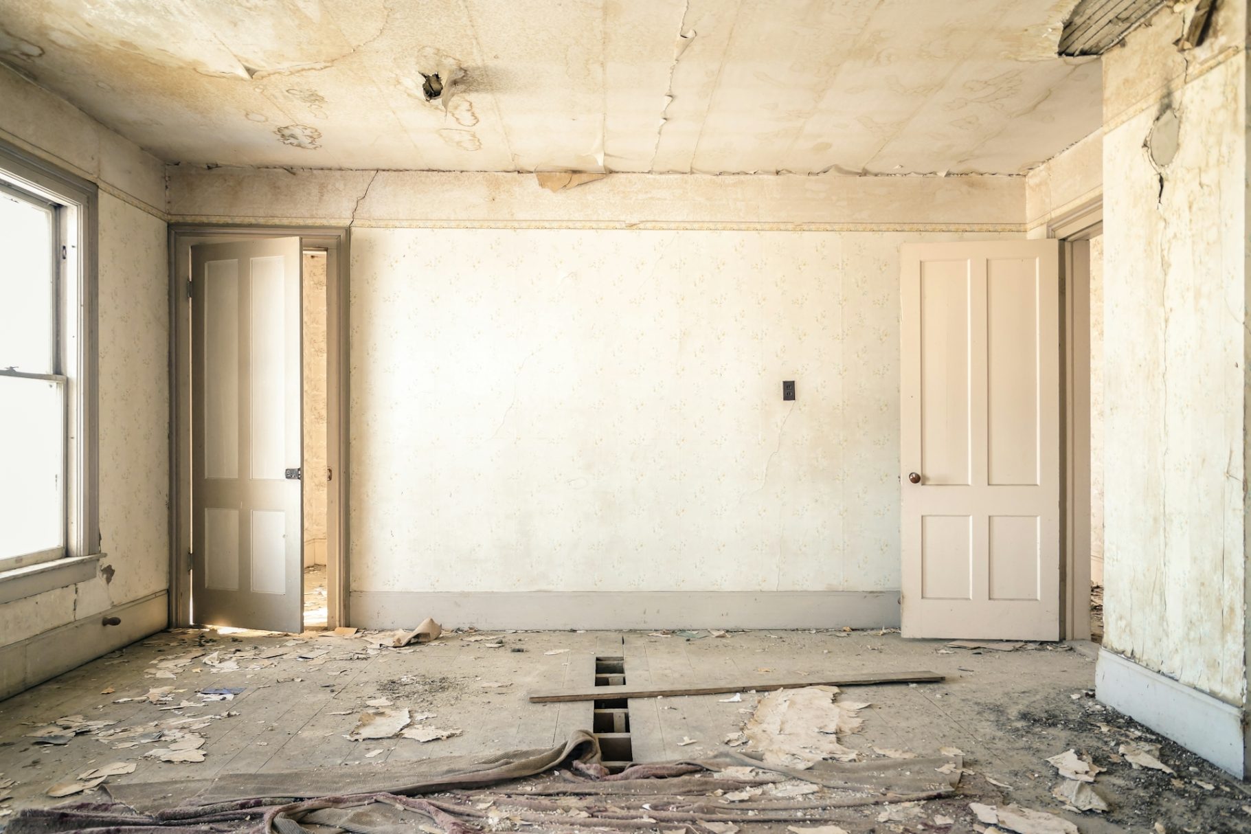 Baustellenendreinigung Leere, verfallene Zimmer mit abblätternder Farbe und Holzresten auf dem Boden.