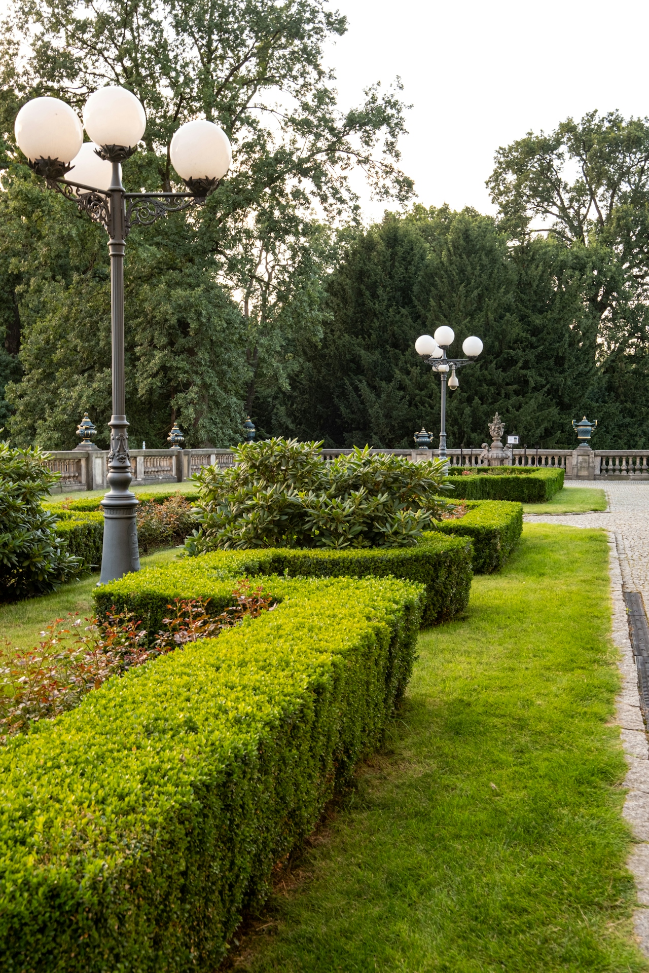 Pflege von Außen- und Grünanlagen Gepflegter Park mit grünen Hecken und Straßenlaternen.